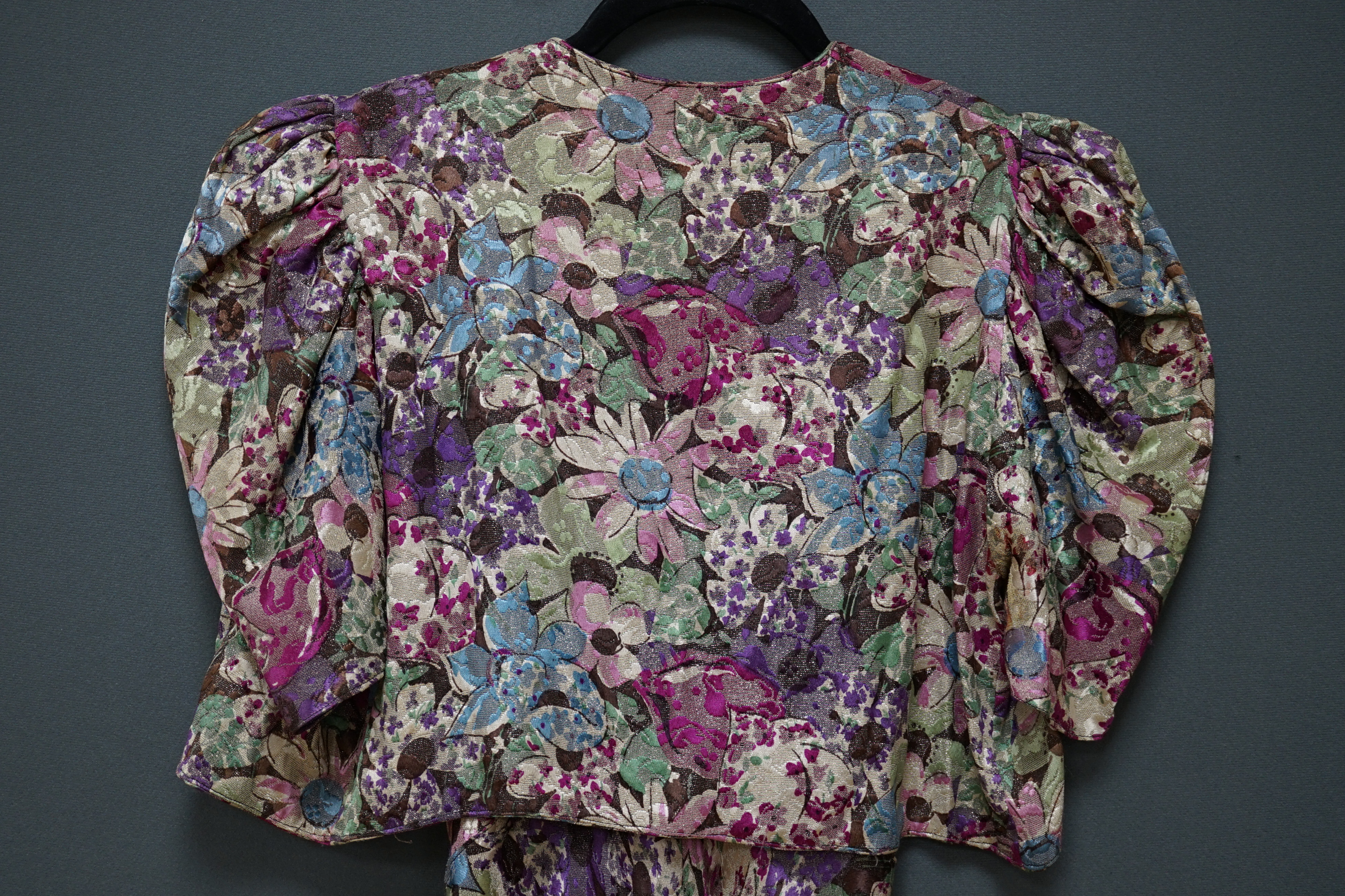 An early 1940’s floral lurex evening dress and bolero, handmade brightly coloured floral lurex, bias cut, with a cross over plunging bodice, half belt and matching bolero, 40cm front bodice arm to arm. Condition - the co